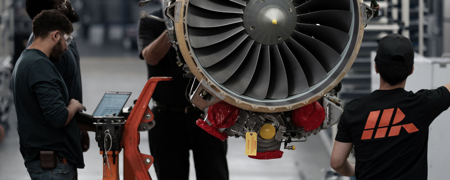 Group working around exposed turbine with visible fan blades, emphasizing scale, teamwork and technical detail.