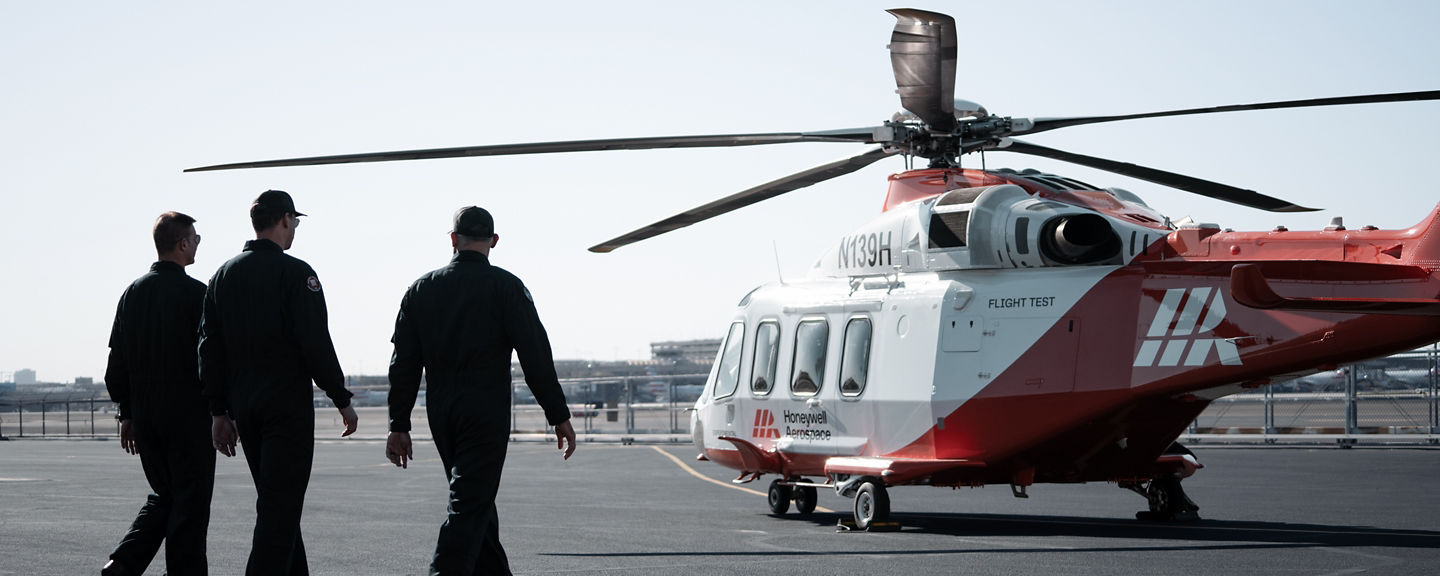 Three crew members approaching rotorcraft under clear sky, representing readiness and coordinated aviation operations.