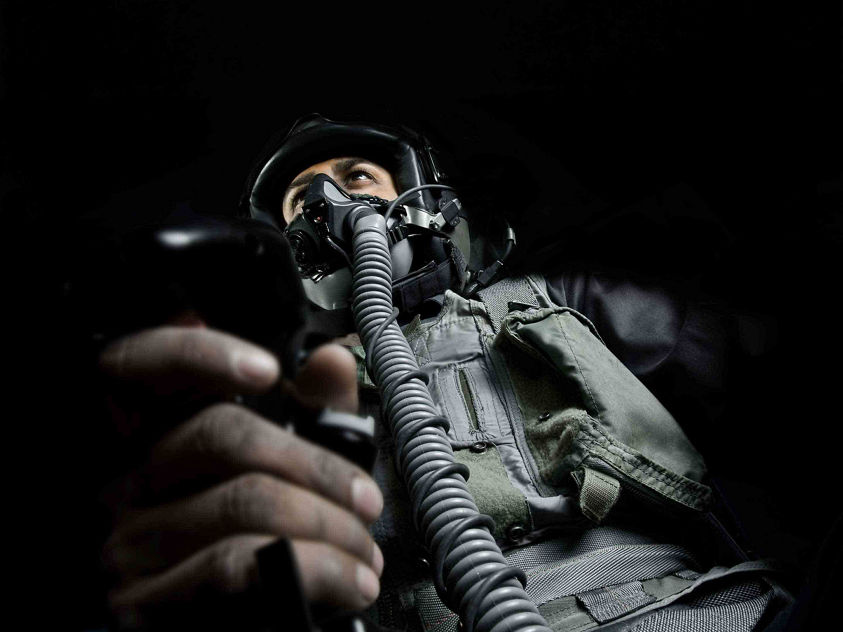 Low-angle cockpit view showing a pilot holding the aircraft control stick during flight operations.