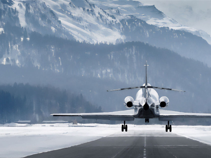 The image depicts a business jet, potentially a Bombardier Global Express XRS, taking off from a snow-covered runway in a mountainous region.